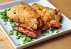 two pieces of chicken on a white plate with green garnishes and parsley