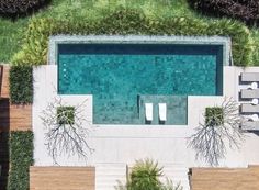 an aerial view of a swimming pool surrounded by grass and wooden decking with lounge chairs