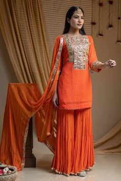 Orange leheriya short kurta with gota embroidered placket. Paired with a sharara and dupatta.
Components: 3
Pattern: Embroidery
Type Of Work: Gota
Neckline: Round Neck
Sleeve Type: Three Quarter Sleeves
Fabric: Cotton, Georgette
Color: Orange
Other Details: 
Kurta:
Gota embroidered cuffs
Sharara:
Gota hem
Dupatta:
Gota border
Occasion: Mehendi and Haldi - Aza Fashions Orange Georgette Sharara With Dabka Work, Orange Chinon Sharara For Eid, Unstitched Orange Sharara With Mirror Work, Orange Sharara With Mirror Work For Eid, Orange Chinon Sets For Diwali, Orange Chinon Festive Set, Festive Orange Chinon Set, Designer Orange Chinon Sharara, Orange Chinon Set With Dupatta