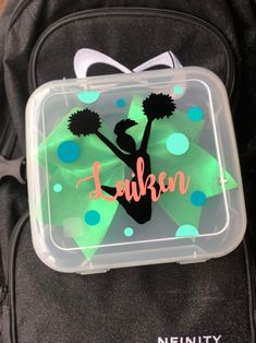 a lunch box with a green and black cheerleader design on the lid that says, lauren