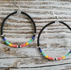 two pairs of beaded hoop earrings on top of a wooden table