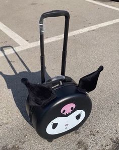 a piece of luggage sitting on top of a parking lot next to a curb with an animal face painted on it