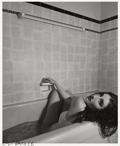 a black and white photo of a woman laying in a bathtub