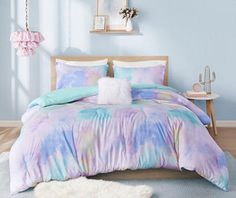 a bed with blue and pink comforters in a room next to a white rug