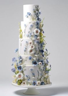 a three tiered wedding cake with blue and white flowers