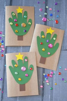 three handprinted christmas trees on brown paper with confetti scattered around them