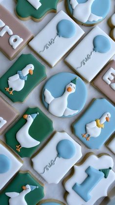 decorated cookies with ducks and letters are arranged on a table top in the shape of squares