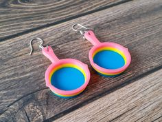 "Show off your pansexual pride and love for puns with these Frying Pan Pride Earrings! 3D printed in 3 colours, these lightweight pan pride earrings are sure to delight! Size: Total Earring Length 2.4\" (60mm). Each Pan is 1.5\"(40mm) tall, 1\" (25mm) wide and .25\"(7mm) thick. Hanging on stainless steel earring hooks. 3D printed from strong, vibrant and waterproof PLA filament." Gay Jewelry, Pan Pride, Pride Earrings, Pride Jewellery, French Wire Earrings, Matching Keychains, Frying Pans, Pansexual Pride, Art Earrings