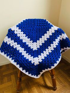 a blue and white afghan sitting on top of a wooden stool