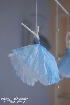 two paper ballerinas hanging from strings in the shape of umbrellas, one blue and one white