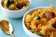 two bowls filled with macaroni and broccoli on top of a blue table