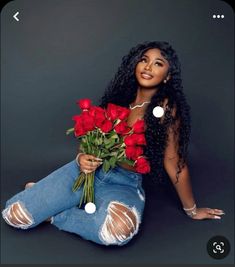 a woman sitting on the ground with roses in her lap