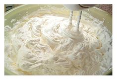 a mixing bowl filled with whipped cream being stirred by an electric beater on top of it