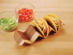 three tacos sitting on top of a wooden cutting board