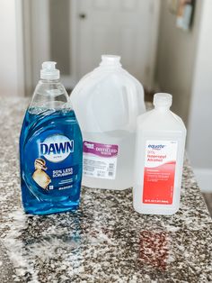 three bottles of dawn and one gallon of dish soap sit on a granite countertop