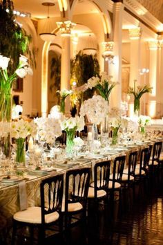 a long table is set up with white flowers and candles for a formal dinner party