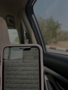 a person holding up a cell phone in their hand with arabic writing on the screen