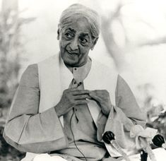 an old woman sitting down with her hands on her chest