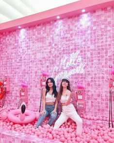 two women sitting on pink balls in front of a wall that says hello valentine's