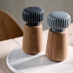 two salt and pepper shakers sitting on top of a white plate next to a wooden chair