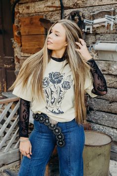 Get wild in The Stetson Tee. With its cropped length and cowboy boots and roses graphic, you'll be the most stylish cowgirl in the room. Made from soft and breathable 100% cotton, this vanilla colored western tshirt is perfect for all your adventures. Haylee is wearing size small paired with The Delmer Jeans , the Bryan Belt and The Annie Mesh Top Graphic Tshirt And Skirt, Western Button Up Shirt Outfit, Western Tshirt Outfits, Lace Undershirt Outfit Long Sleeve, Long Sleeve Lace Top Outfit, Country Shirt Ideas Vinyl, Mesh Undershirt Outfit, Black Lace Shirt Outfit, White Lace Shirt Outfit