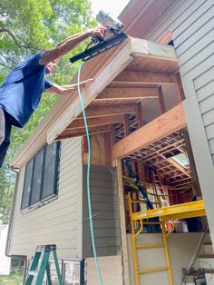 a man is working on the roof of a house that's being built with tools