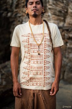 a man with dreadlocks standing in front of a stone wall wearing a necklace