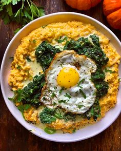 a bowl filled with mashed potatoes topped with an egg and spinach on top