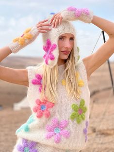 a woman wearing a white sweater with flowers on it and a knitted hat over her head