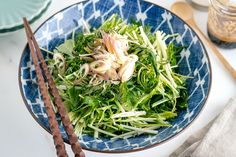 a blue and white bowl filled with food next to chopsticks on top of a table