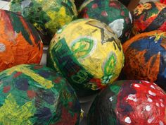 many colorful balls are sitting on the ground with paint splattered all over them