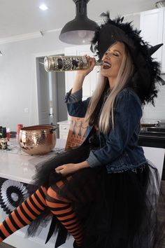 a woman dressed as a witch drinking from a cup