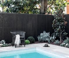 a small pool with a chair next to it in the middle of a garden area