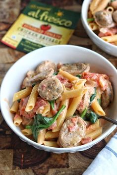 two bowls filled with pasta and meatballs on top of a wooden table next to a packet of alfredo