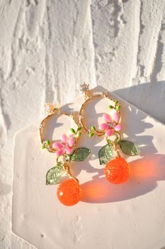 "AMALFI crown translucent tangerine orange earrings, czech glass tangerine earrings, food earrings, mandarin fruit earrings, custom earrings These Tangerine Crown of Flowers Gold Plated Earrings are a stunning piece of jewelry that will instantly elevate any outfit. The earrings feature delicate gold plating that forms a crown-like design, adorned with beautiful flowers and leaves. The centerpiece of the earrings is a dazzling transluscent tangerine orange( or mandarin) Czech crystal, adding a pop of color and sparkle to the design. These earrings have a timeless elegance that will transport you to the picturesque Amalfi Coast in Italy with every wear. Whether you're dressing up for a special occasion or simply adding a touch of glamour to your everyday look, these earrings are sure to tur Orange Jewelry With Fruit Design For Gifts, Orange Fruit Design Jewelry For Gift, Orange Fruit Design Jewelry Gift, Cute Orange Jewelry For Party, Cute Orange Party Jewelry, Nickel Free Orange Jewelry For Party, Nickel-free Orange Jewelry For Party, Cute Orange Dangle Jewelry, Cute Nickel-free Orange Jewelry