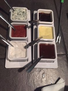 four different sauces in small dishes with spoons