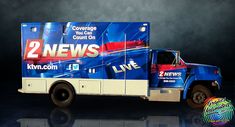 a truck advertising two news on it's side in front of a dark background