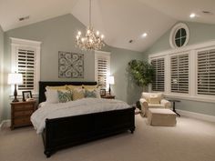 a bedroom with a large bed and chandelier hanging from the ceiling