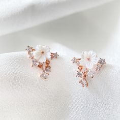 These stunning earring studs are crafted in rose gold and feature a delicate white mother of pearl flower with a sparkling cubic zirconia drop. Add a touch of elegance and radiance to your ensemble with these beautiful earrings. Perfect for your everyday wear. They are hypoallergenic with silver post earring pins to prevent allergy. Material: Mother-of-pearl, Cubic Zirconia, Silver Post Size: 1.6cm (Length) ✨More hypoallergenic earrings: https://www.etsy.com/ca/shop/SisiliaJewels?section_id=4854 White Cubic Zirconia Flower Bridal Earrings, Rose Gold Cubic Zirconia Flower Earrings For Party, Elegant Rose Gold Cluster Earrings For Party, Party Rose Gold Pearl Earrings With Cubic Zirconia, Elegant Rose Gold Cubic Zirconia Flower Earrings, Elegant Rose Gold Flower Clip-on Earrings, Elegant Rose Gold Flower Shape Cluster Earrings, Delicate White Crystal Earrings For Gift, Elegant White Cubic Zirconia Flower Earrings