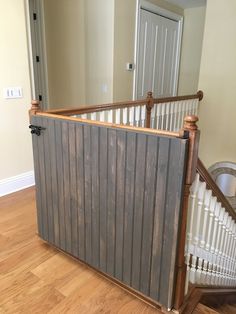 a wooden gate sitting in the middle of a living room next to a stair case