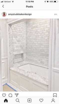 an instagram photo of a bathroom with white tile and marble tub, built - in shelving