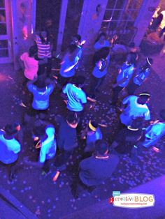 a group of people standing around each other in a room with blue and purple lights