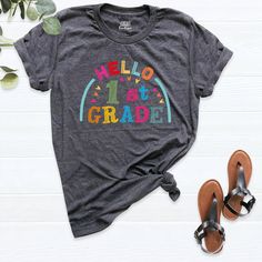 a t - shirt with the words hello 1st grade on it next to some sandals