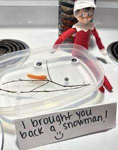 an elf is sitting on top of a stove with a sign that says, i brought you back a snowman