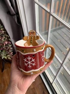 a hand holding a red and white mug with a bear on it's side