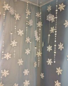 snowflakes are hanging from the ceiling in front of a curtain that is decorated with beads