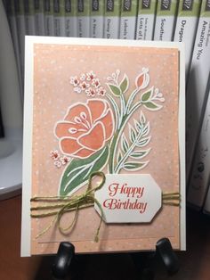 a happy birthday card with flowers and a price tag on the front, sitting next to some books