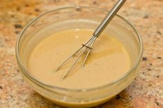 a glass bowl filled with liquid and two metal whisks sticking out of it