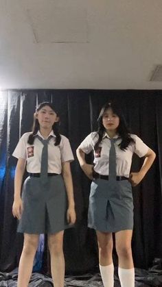 two girls in school uniforms standing next to each other with their hands on their hips