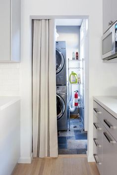 an open door leading to a washer and dryer in a small room with white cabinets